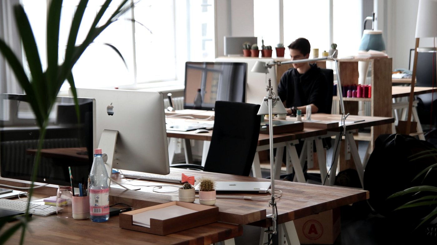 Small office with wooden desks, computers and chairs